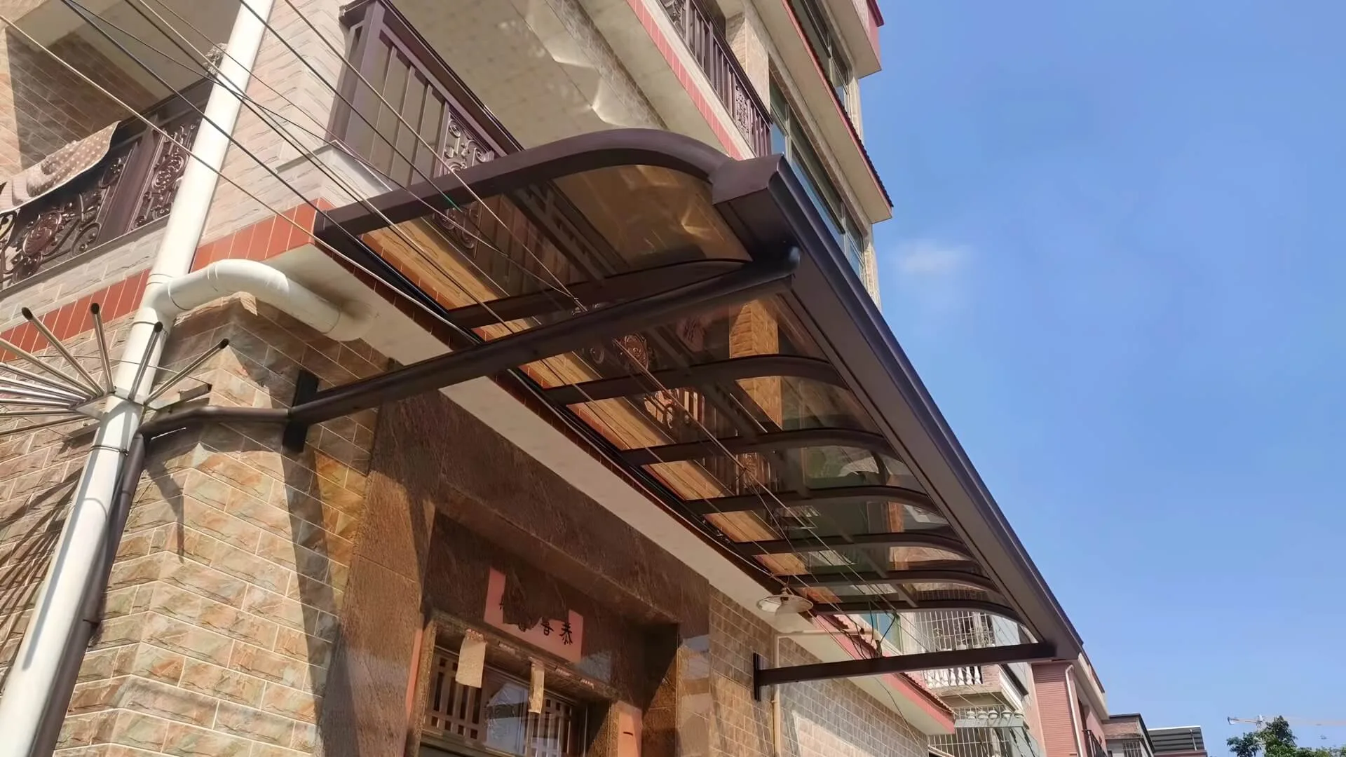 Classic wall-mounted patio cover featuring a heavy-duty bronze aluminum frame and tinted polycarbonate roof, representing our premium customizable canopies for wholesale distribution.