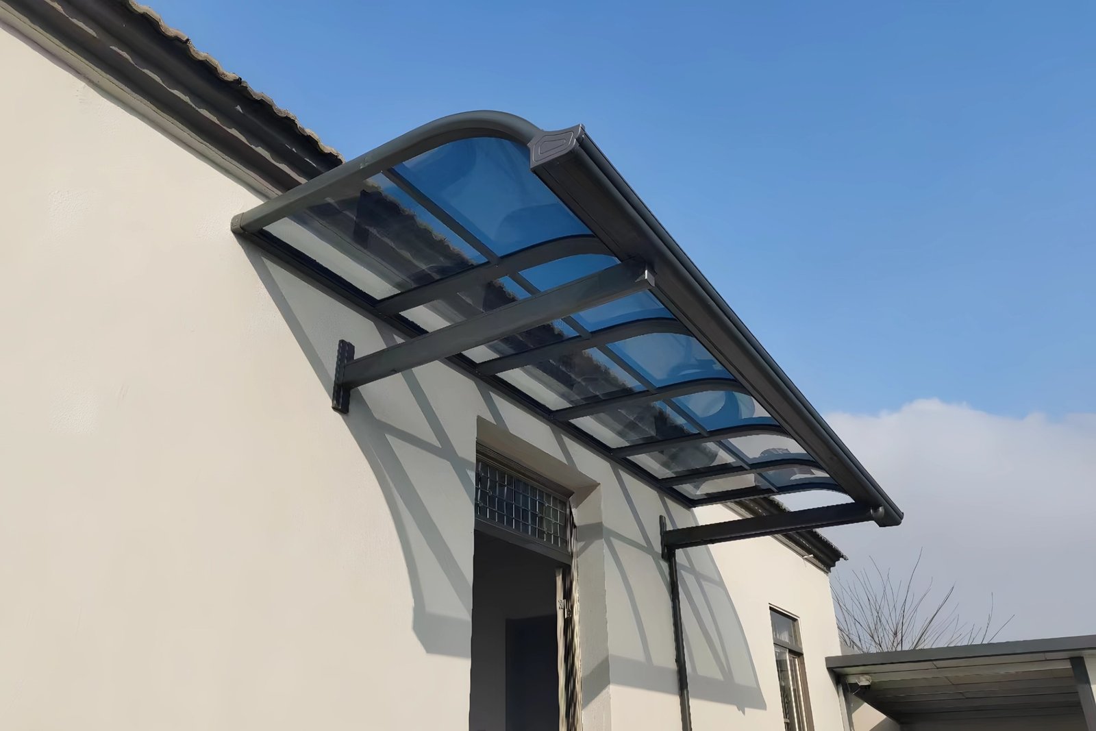 A continuous multi-unit installation of aluminum verandas with dark frames and arched blue polycarbonate roof panels, showcasing the modular expansion system for extensive commercial outdoor extensions.