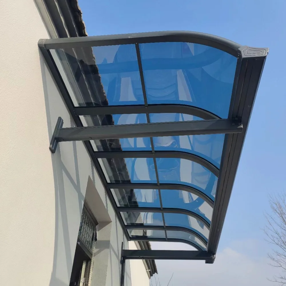 Installed curved wall-mounted aluminum patio cover featuring a dark rust-proof frame and high-impact blue polycarbonate roof panels, demonstrating seamless facade integration.