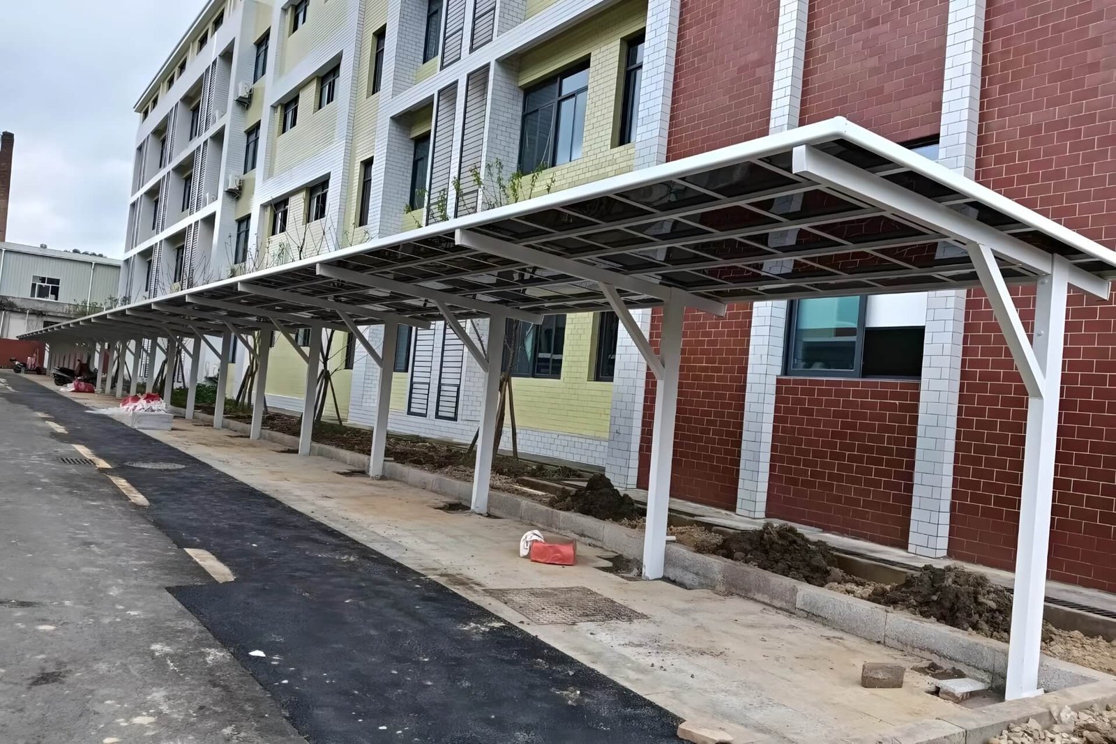 Long row of custom white cantilevered aluminum carports installed along a residential building, providing durable weather protection for community vehicles.