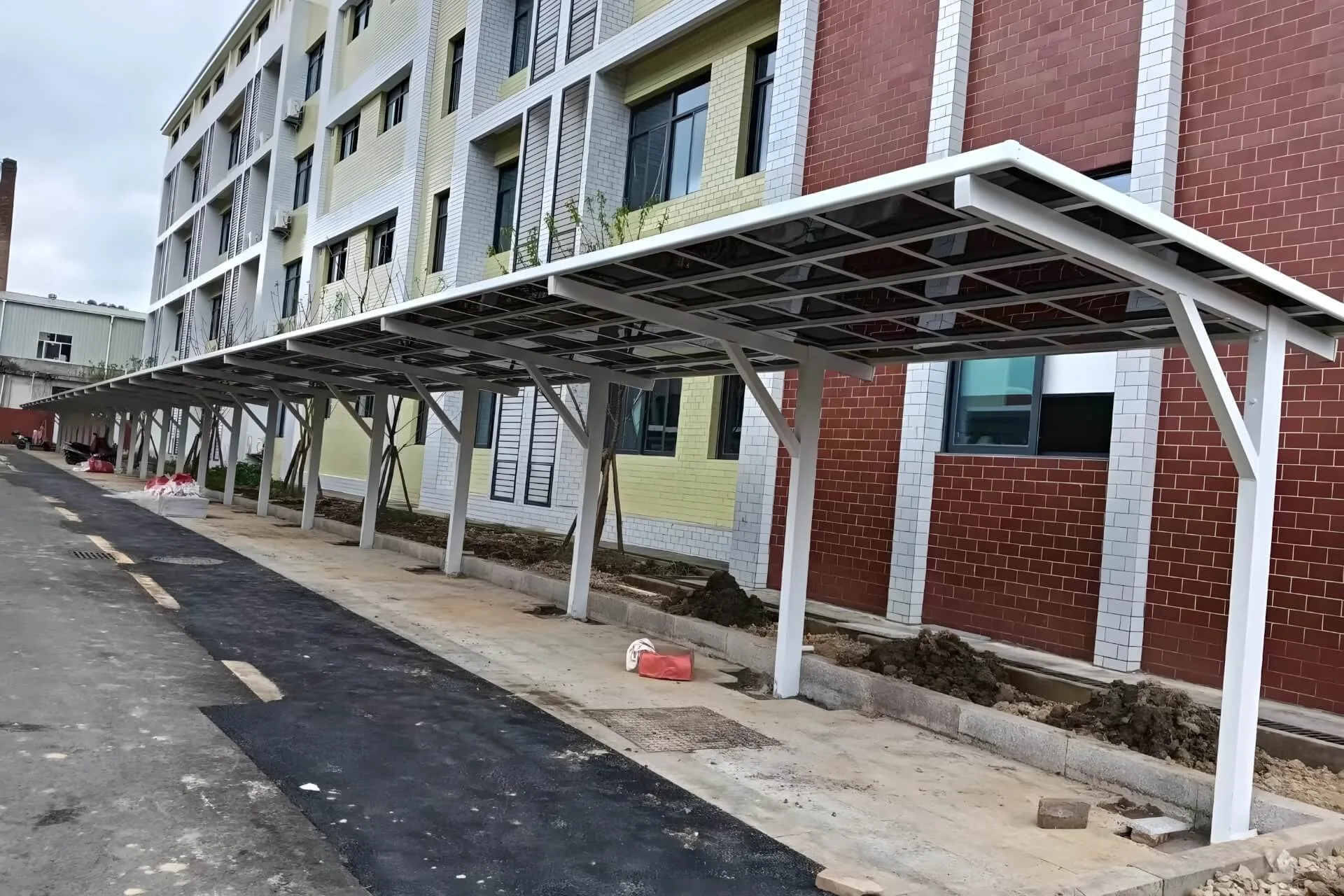 Long row of custom white cantilevered aluminum carports installed along a residential building, providing durable weather protection for community vehicles.