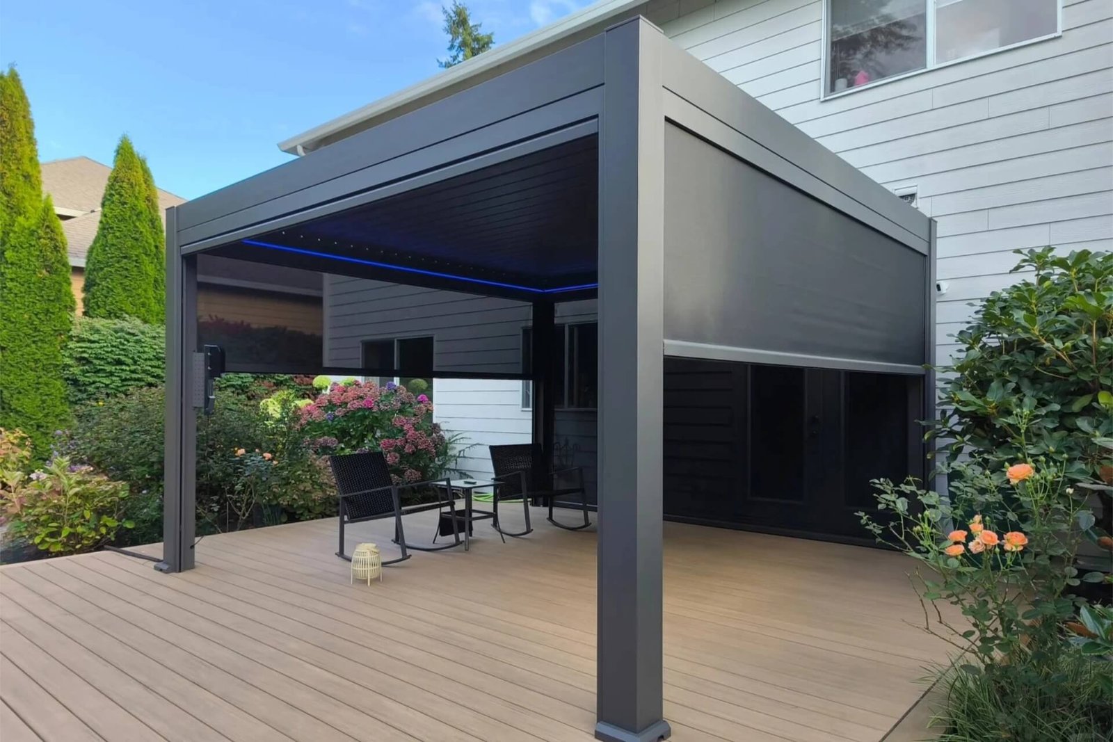 Custom dark grey aluminum pergola installed in a California backyard, featuring half-lowered windproof zip screens and unique waterproof ice blue LED lighting.