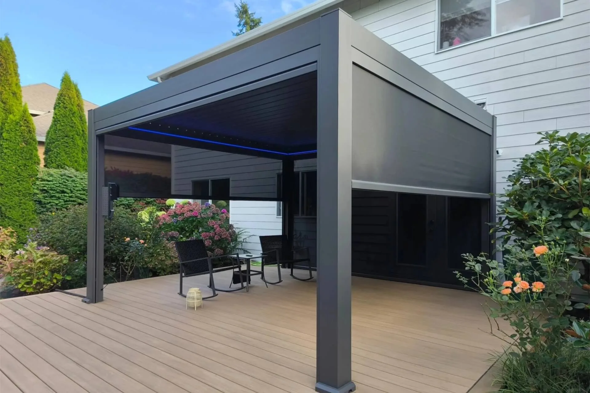 Custom dark grey aluminum pergola installed in a California backyard, featuring half-lowered windproof zip screens and unique waterproof ice blue LED lighting.