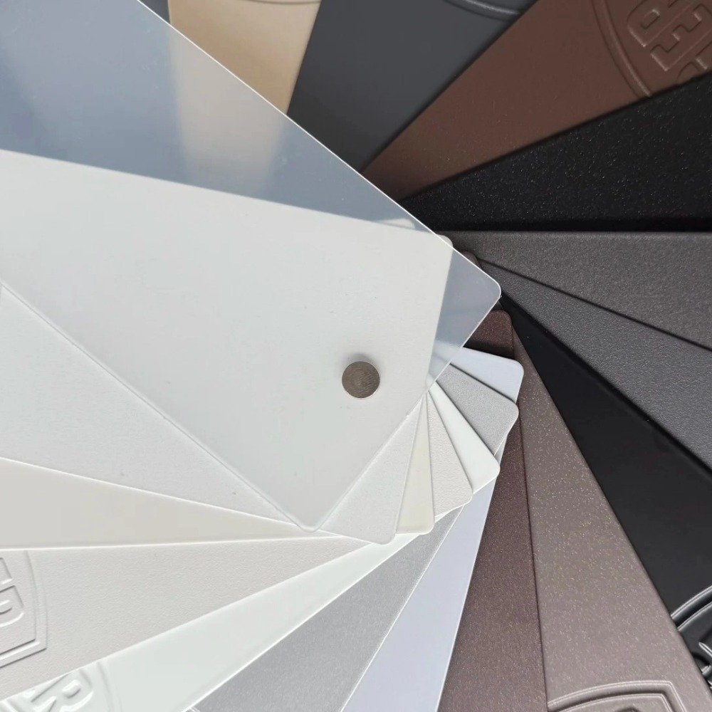 Close-up of premium powder-coated aluminum color swatches in various shades like white, grey, and bronze, representing custom frame finish options for commercial carports.