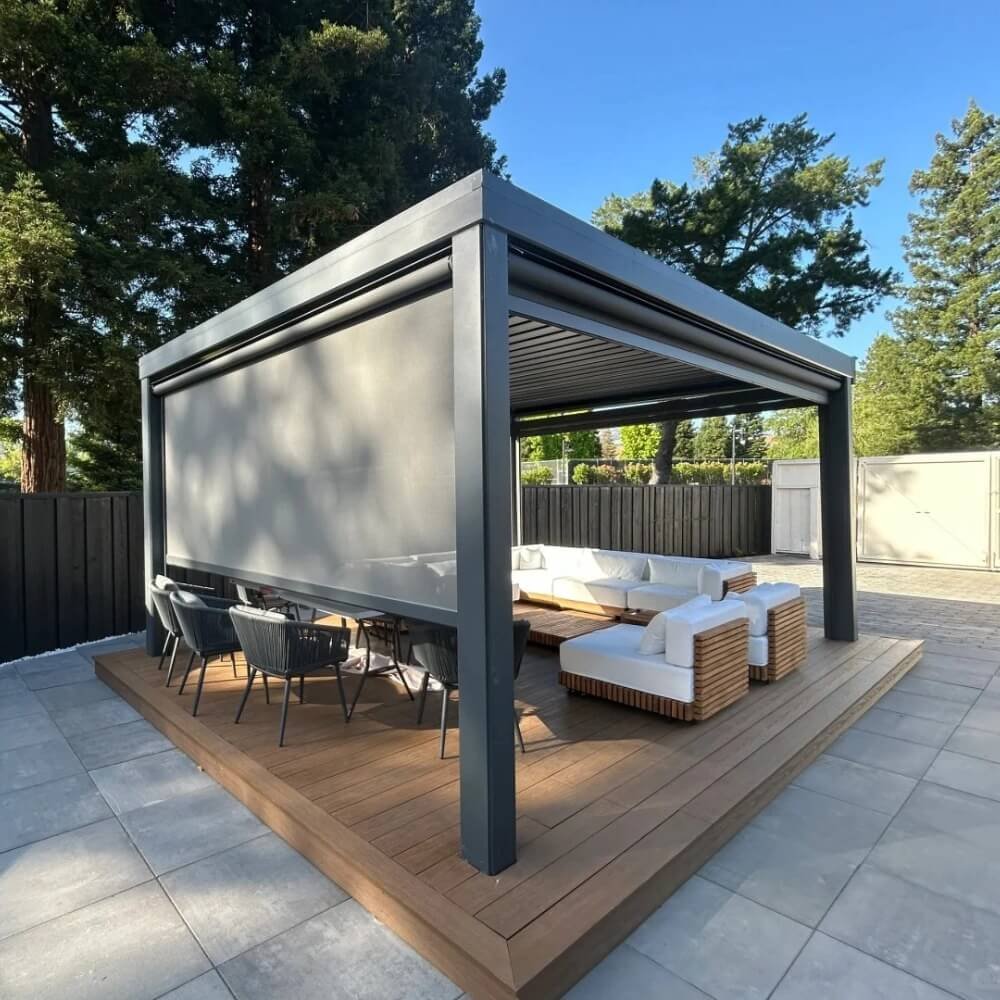 Premium dark grey freestanding aluminum bioclimatic pergola featuring integrated drop-down zip screens, installed on a wooden deck for luxury outdoor living solutions.