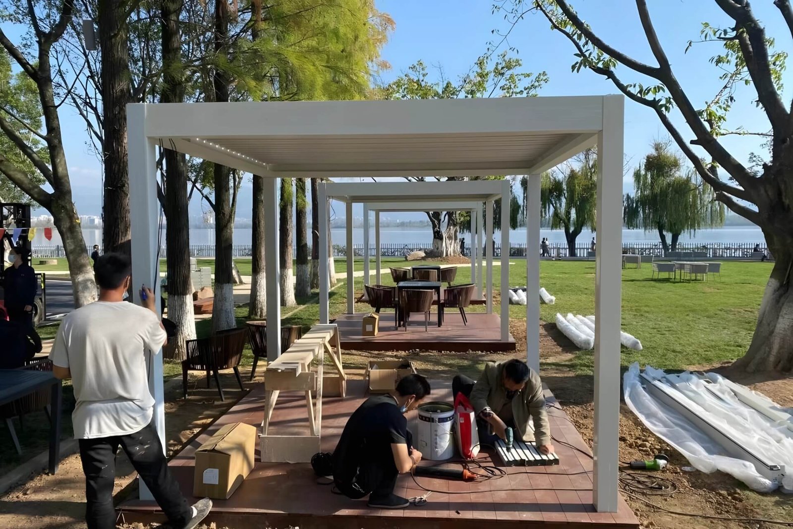 Professional installation team wiring the LED system for a custom white aluminum pergola in a Guangzhou public park.