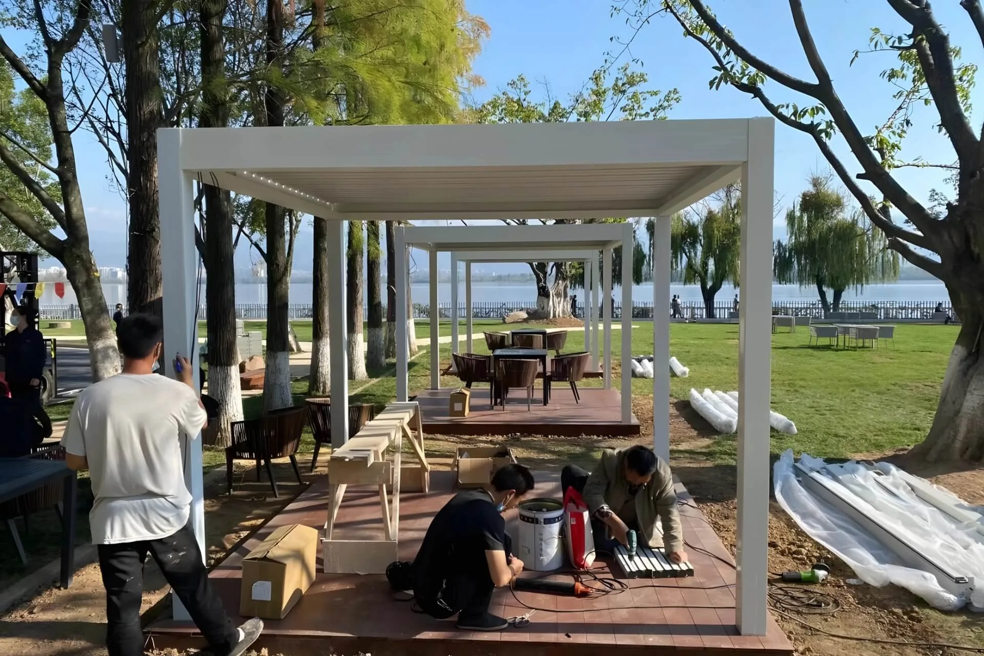 Professional installation team wiring the LED system for a custom white aluminum pergola in a Guangzhou public park.