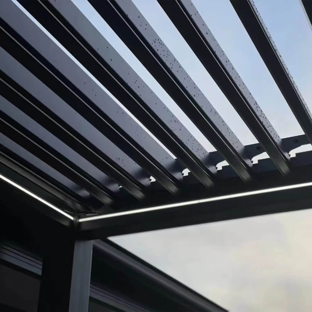 Close-up view of waterproof integrated LED lighting strips built seamlessly into the dark grey aluminum louvers of a bioclimatic pergola.