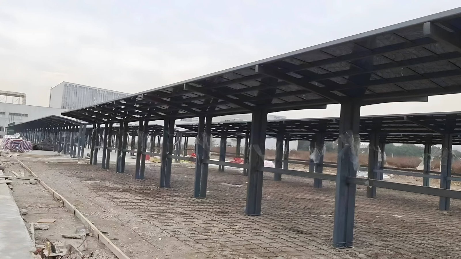 Real-world construction site of a massive continuous aluminum carport system, showcasing heavy-duty structural pillars and framework, demonstrating our capacity for large-scale commercial parking projects.