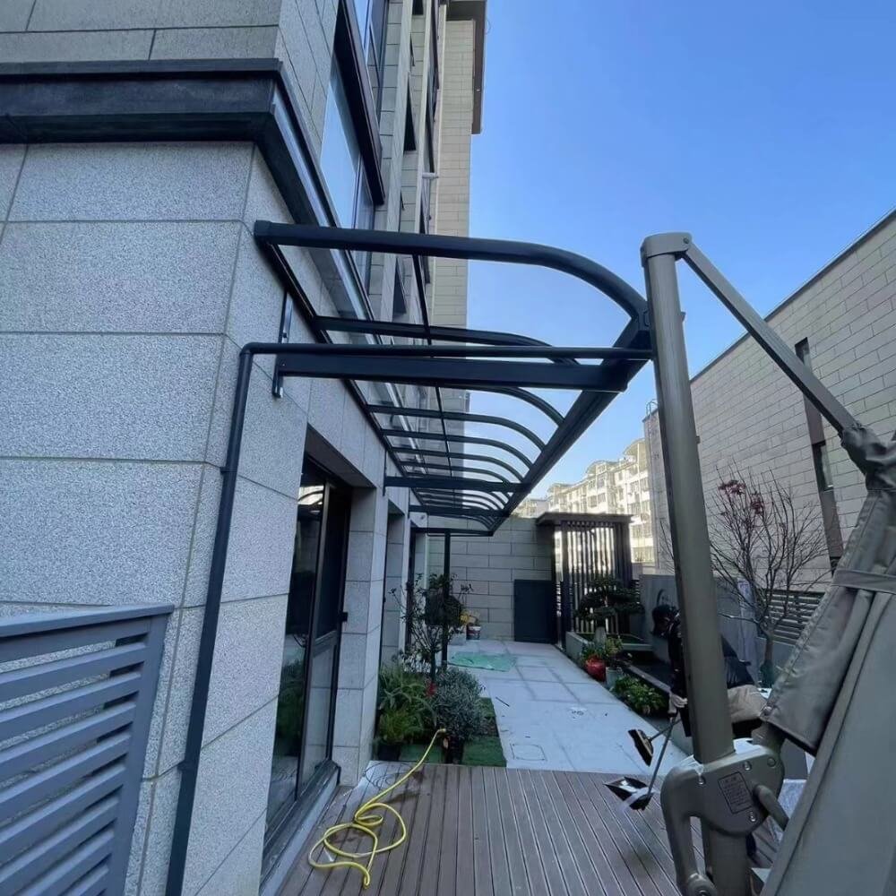 Long continuous wall-mounted aluminum patio cover installed along a building facade, demonstrating our modular extension system for extensive outdoor terrace coverage.