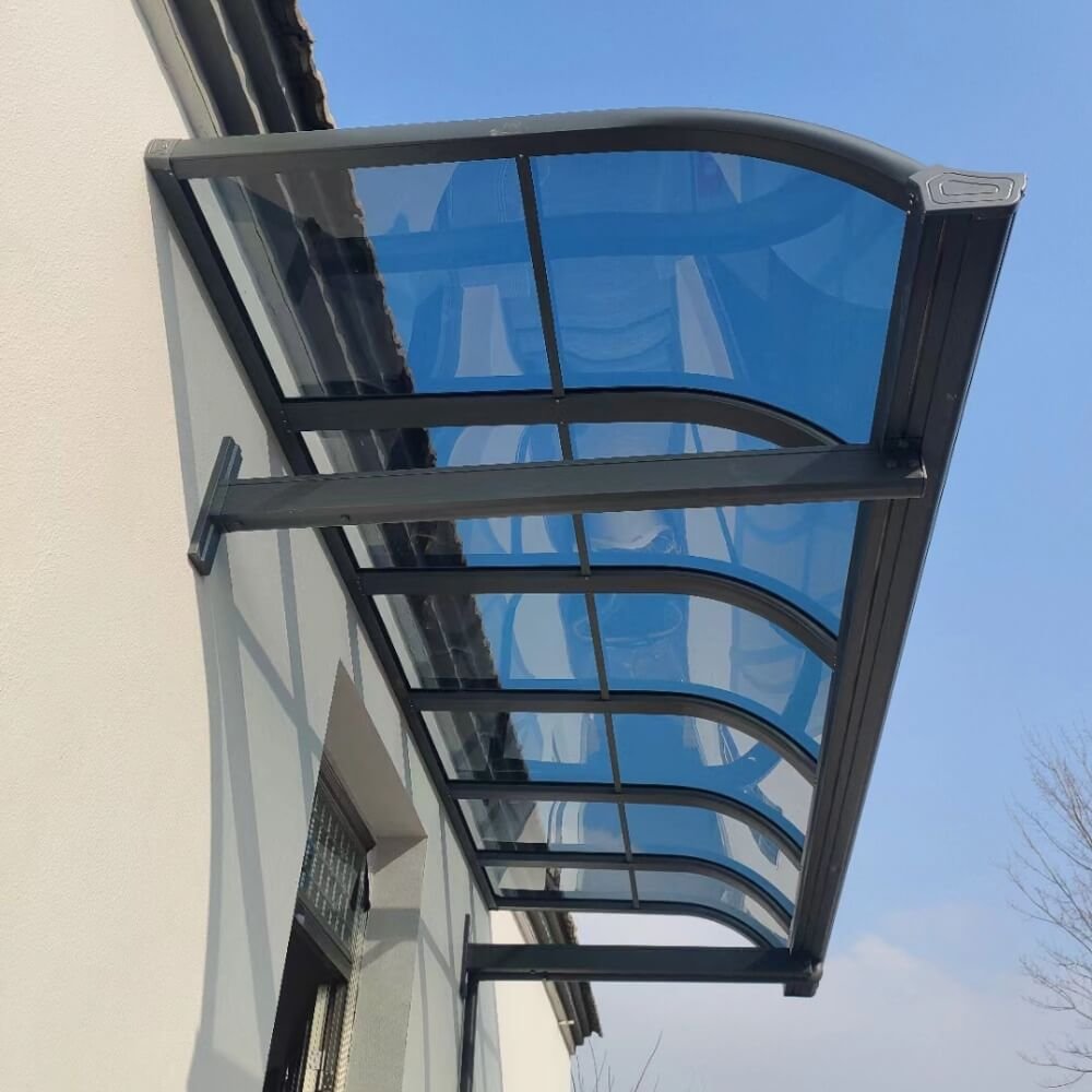 Heavy-duty wall-mounted aluminum patio cover with tinted blue polycarbonate roof panels, providing durable weather protection for outdoor verandas and residential terraces.