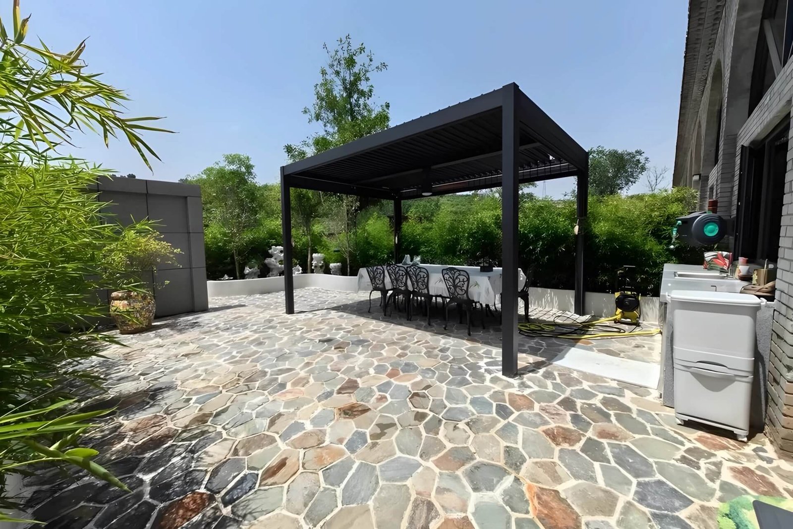 black motorized aluminum pergola installed on a stone patio at a moroccan boutique hotel