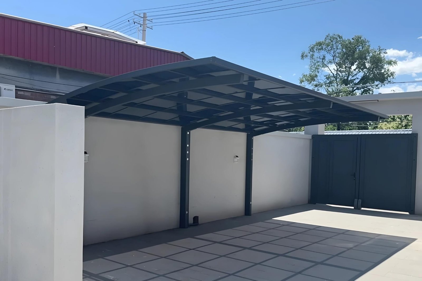 A custom dark brown cantilever aluminum carport installed in a Saudi Arabian courtyard, providing intense UV protection and cooling shade for a parked motorcycle.
